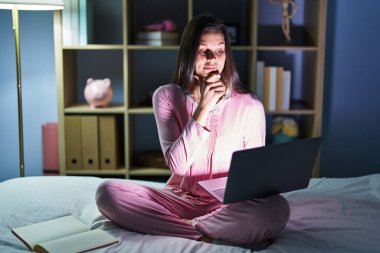 Genç İspanyol kadın, elleri çenesinde bilgisayar dizüstü bilgisayar kullanıyor. Soru sormayı, düşünceli ifadeyi düşünüyor. Gülümseyen ve düşünceli bir yüz. şüphe kavramı. 