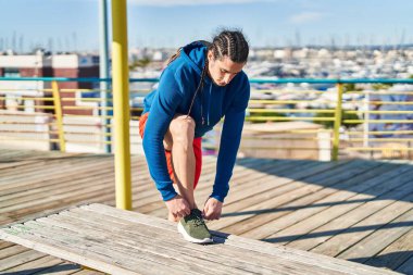 Young man tying shoe at seaside