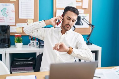 Genç İspanyol iş adamı. Akıllı telefondan konuşuyor. Ofise bakıyor.