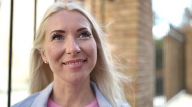 Young blonde woman smiling confident looking to the side at street