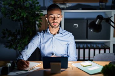 Geceleri ofiste çalışan Latin asıllı genç adam yüzünde ciddi bir ifadeyle rahatladı. Basit ve doğal bir şekilde kameraya bakıyorsun.. 