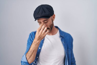 Soyutlanmış arka planda duran, burnu ve gözleri ovuşturmaktan yorgun düşmüş, yorgun ve başı ağrıyan İspanyol bir adam. Stres ve hüsran kavramı. 