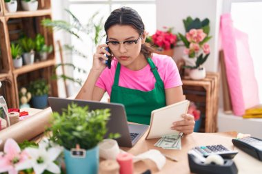 Çiçekçide dizüstü bilgisayar kullanarak konuşan İspanyol bir çiçekçi kadın.