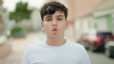 İkili olmayan adam gülümsüyor. Kendine güveni tam. Park ağzıyla komik jestler yapıyor.