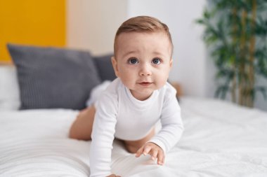 Yatak odasında beyaz bebek yatakta emekliyor.