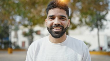 Parkta kendinden emin gülümseyen İspanyol genç adam.