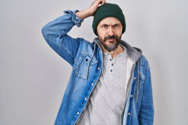 Yün şapka takan ve soru soran İspanyol dövmeli genç bir adam. Şüpheyle kararsız, kafa kafaya düşünerek. Düşünceli kavram. 