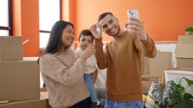 Çift ve oğul, ellerinde anahtarlarla akıllı telefondan selfie çekiyorlar.