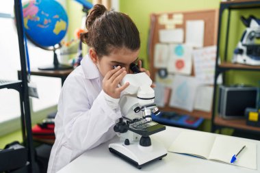 Laboratuvar sınıfında mikroskop kullanan sevimli İspanyol kız öğrenci.