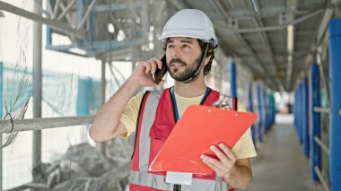 Genç İspanyol müteahhit, akıllı telefon okuyarak sokakta konuşuyor.