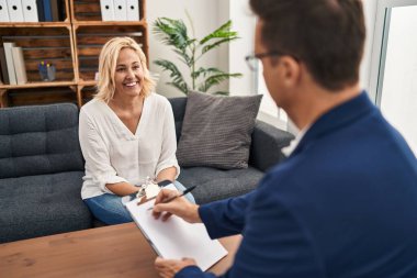 Yüzünde mutlu ve havalı bir gülümsemeyle psikoloji terapi ofisinde orta yaşlı bir kadın. şanslı kişi. 