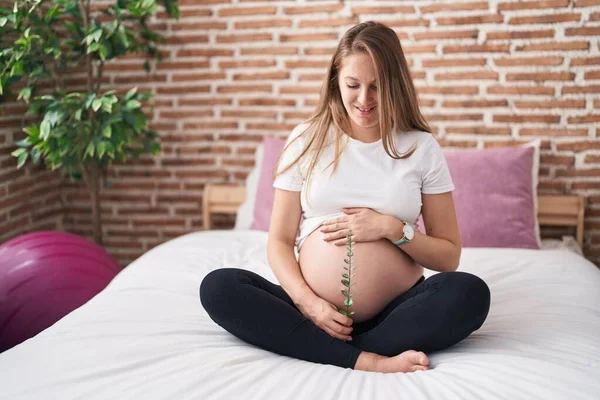 Jonge Zwangere Vrouw Aanraken Buik Holding Plant Slaapkamer — Stockfoto