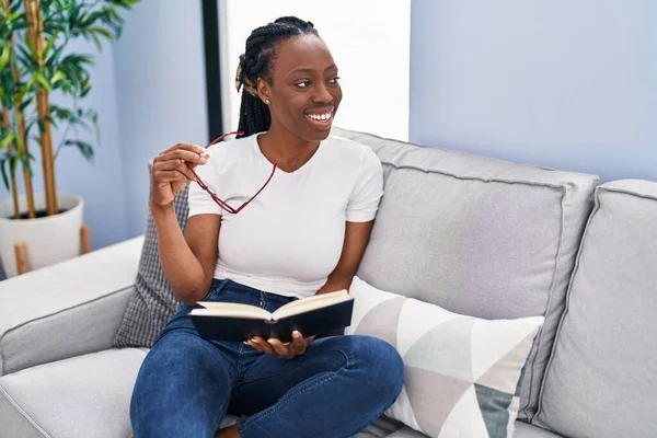 African American Woman Reading Book Sitting Sofa Home — Φωτογραφία Αρχείου