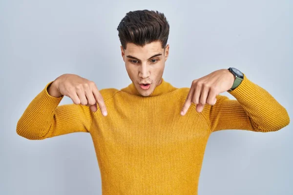 Mavi Arka Planda Dikilen Genç Spanyol Adam Parmaklarını Göstererek Reklamını — Stok fotoğraf