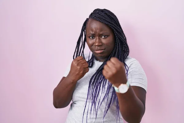 ピンクの背景に立っている若いアフリカの女性は 拳の防衛ジェスチャー 怒りと動揺の顔 問題を恐れて戦う準備ができて — ストック写真