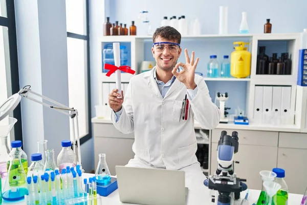 在科学家实验室工作的年轻人手握毕业证书 手握手签 微笑友好的手势 表示出极好的象征 — 图库照片