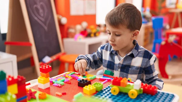 幼稚園のテーブルの上に座っている建設ブロックで遊んで愛らしい白人少年 — ストック写真