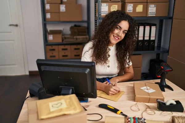 若い美しいヒスパニック女性Eコマースビジネス労働者がオフィスでパッケージに書いている — ストック写真