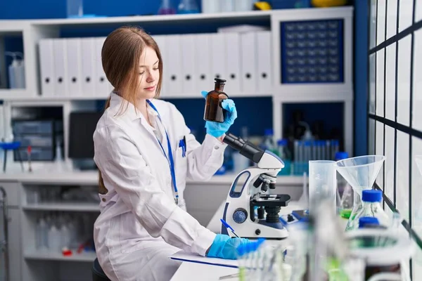 Young Caucasian Woman Scientist Write Document Holding Bottle Laboratory — Stockfoto