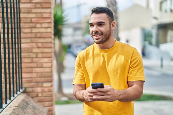 Молодой Латиноамериканец Уверенно Улыбается Используя Смартфон Улице — стоковое фото