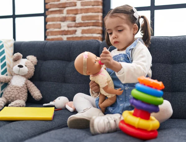 Entzückende Hispanische Mädchen Spielen Mit Baby Puppe Sitzt Auf Sofa — Stockfoto