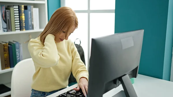 Young Blonde Woman Student Using Computer Stressed University Classroom — стоковое фото