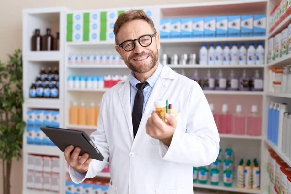 Middle Age Man Pharmacist Using Touchpad Working Holding Pills Bottle — Stock Photo, Image