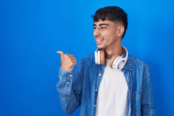 Молодой Латиноамериканец Стоящий Синем Фоне Улыбающийся Счастливым Лицом Смотрящий Указывающий — стоковое фото