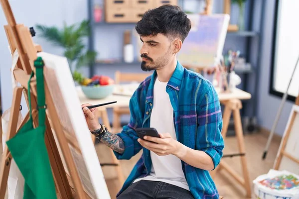 在艺术工作室用智能手机绘图的年轻的恐慌男艺术家 — 图库照片