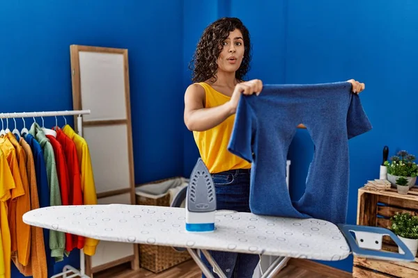 年轻的拉丁女人拿着烧焦的铁T恤在洗衣房 — 图库照片