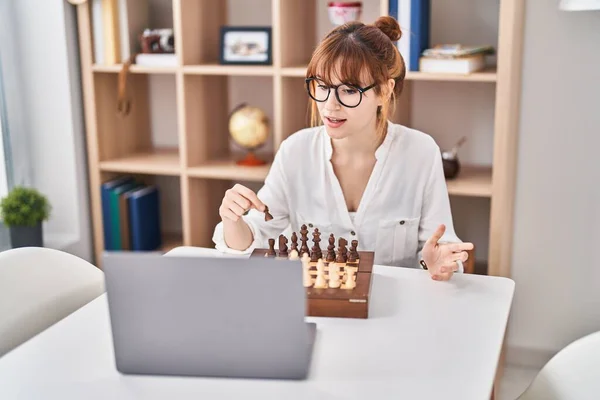 stock image Young woman playing online chess game at home
