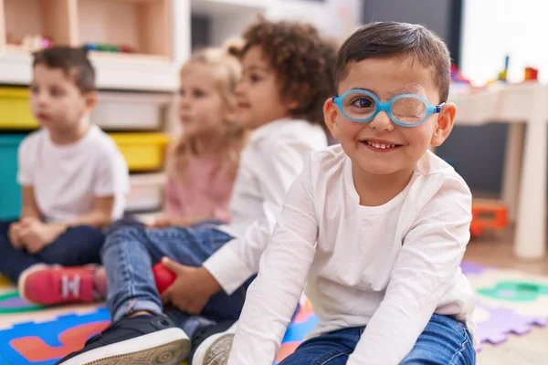 Grupa Dzieci Siedzi Podłodze Uśmiechnięta Pewnie Przedszkolu — Zdjęcie stockowe