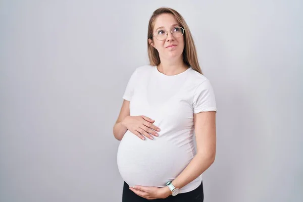 妊娠中の若い女性が赤ちゃんを期待し 妊娠中の腹に触れ 横を見て笑って離れて考えを見つめます — ストック写真