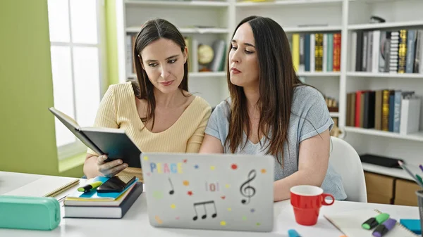 図書館大学のノートパソコン読書本を使って勉強している二人の女性 — ストック写真