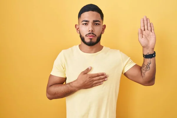 Ung Latinamerikansk Man Står Över Gul Bakgrund Svär Med Handen — Stockfoto