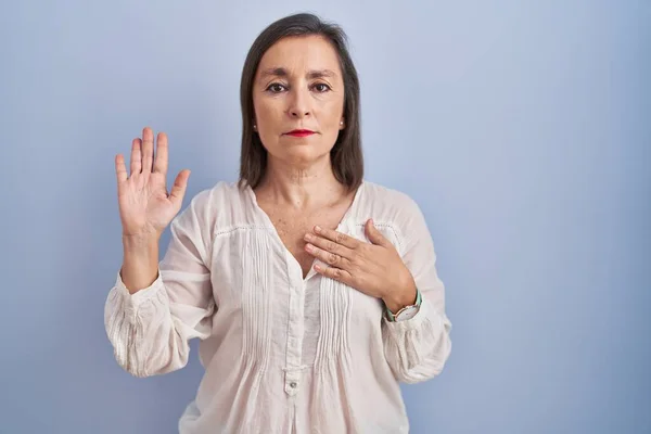 Midaldrende Spansktalende Kvinde Stående Blå Baggrund Sværger Med Hånden Brystet - Stock-foto