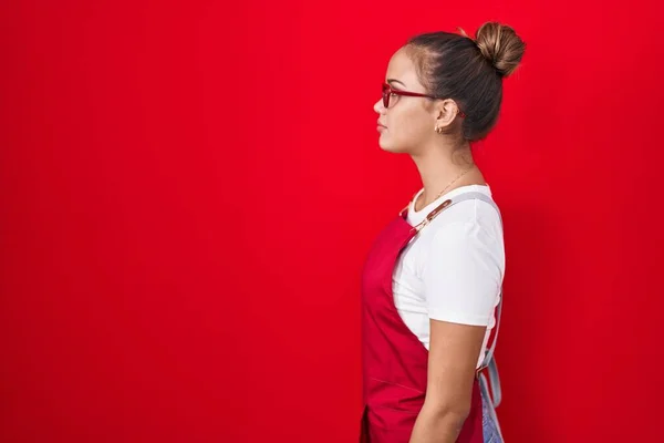 Kırmızı Arka Planda Garson Önlüğü Giyen Genç Spanyol Kadın Yan — Stok fotoğraf