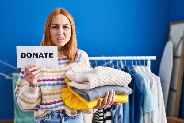 stock image Young woman holding donations for charity clueless and confused expression. doubt concept. 