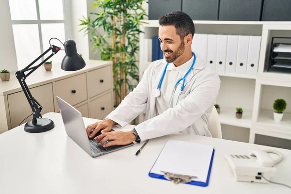 Young Hispanic Man Wearing Doctor Uniform Using Laptop Working Clinic — Stock Photo, Image
