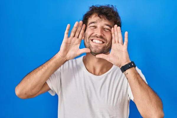 Hispánský Mladík Který Stojí Nad Modrým Pozadím Radostně Usmívá Vykukuje — Stock fotografie