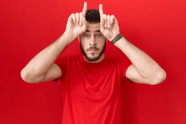 Latin Asıllı Genç Adam Sıradan Kırmızı Tişörtler Giyip Parmağıyla Boynuz — Stok fotoğraf