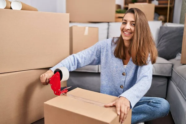 Young woman packing cardboard box at new home