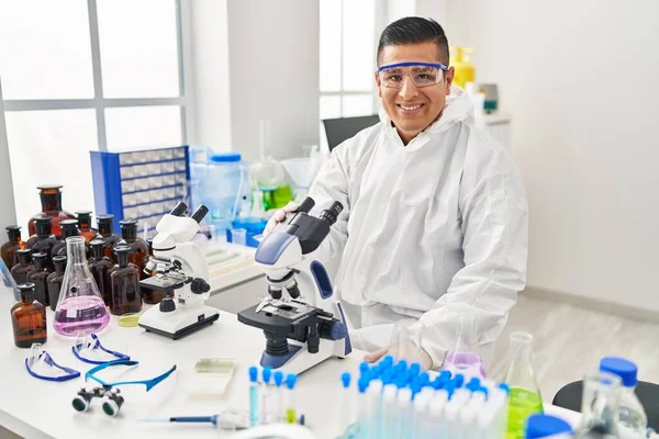 Νεαρός Λατίνος Επιστήμονας Που Φοράει Στολή Προστασίας Covid Χρησιμοποιώντας Μικροσκόπιο — Φωτογραφία Αρχείου