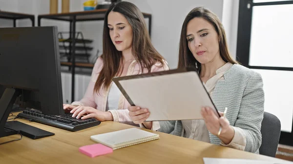 两名在办公室使用计算机阅读文件的女商业工作人员 — 图库照片