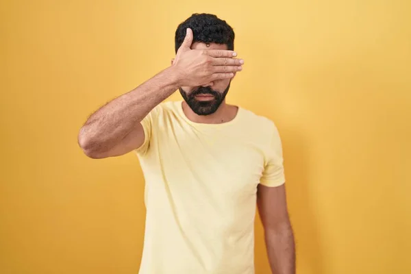 Hispanic Man Beard Standing Yellow Background Covering Eyes Hand Looking — Stock Photo, Image