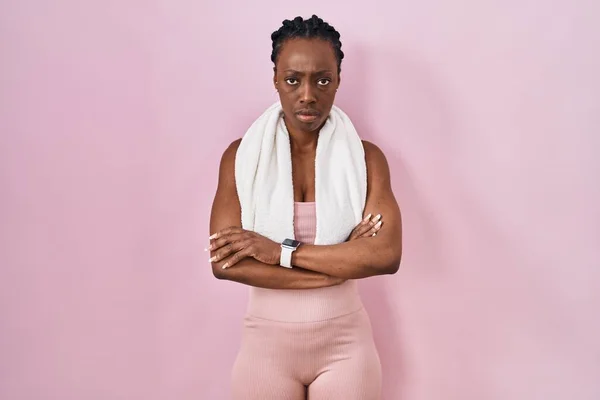 ピンクの背景にスポーツウェアとタオルを身に着けている美しい黒人女性は懐疑的で緊張し 両腕を組んで顔に不承認の表現 否定的な人 — ストック写真