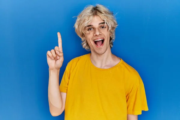 Mladý Moderní Muž Stojící Nad Modrým Pozadím Ukazující Ukazující Prstem — Stock fotografie