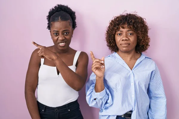 Duas Mulheres Africanas Sobre Fundo Rosa Apontando Para Lado Preocupado — Fotografia de Stock