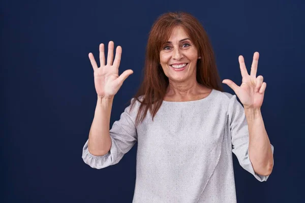 中年妇女站在蓝色的背景上 用八号手指指指指点点 面带微笑 自信而快乐 — 图库照片