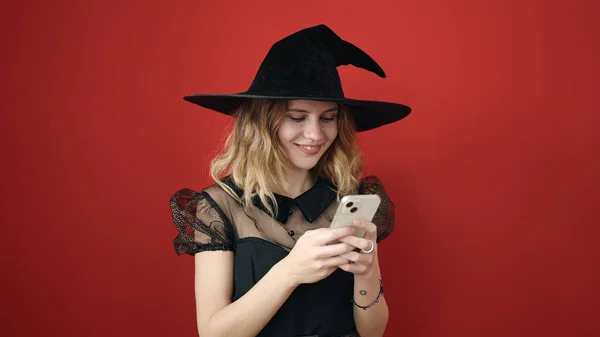 Young Blonde Woman Wearing Witch Costume Using Smartphone Isolated Red — Fotografia de Stock